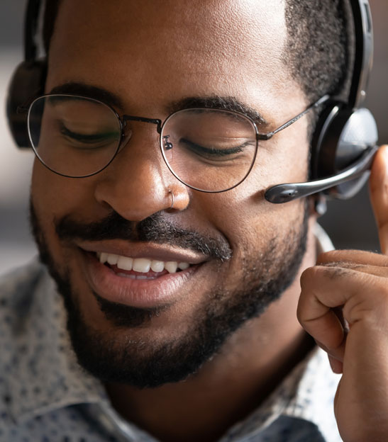 Persona con auriculares y sonriendo durante una llamada.